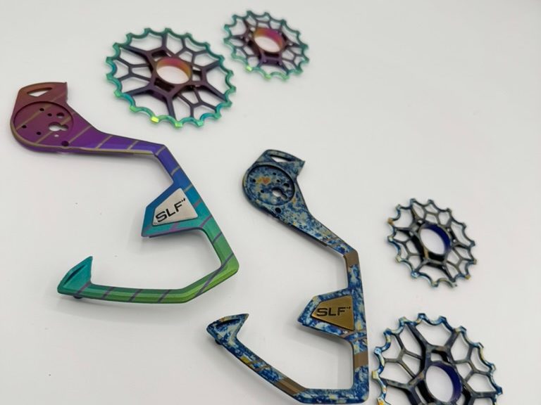 SLF Motion titanium derailleur cages and pulley wheels anodized in a violet-to-green fade and a blue splatter