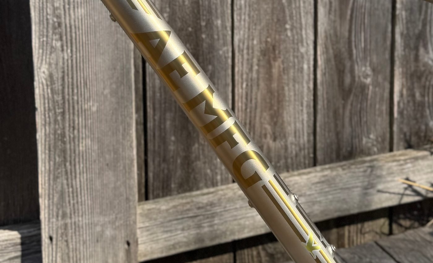 Gold anodized wordmark running down a champagne titanium down tube